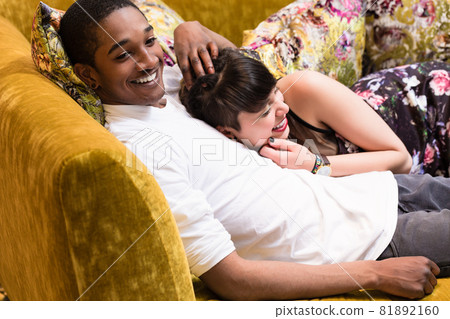Diversity Couple relaxing on sofa 81892160