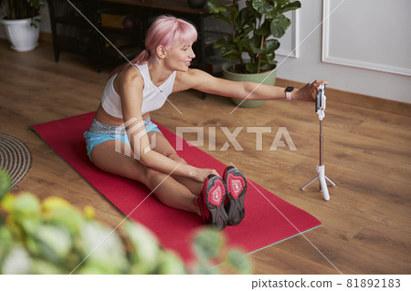 Pink haired lady adjusts smartphone preparing to shoot video tutorial at home 81892183