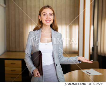 Smiling female entrepreneur with briefcase inviting to negotiate Smiling female entrepreneur with briefcase inviting to negotiate 81892595