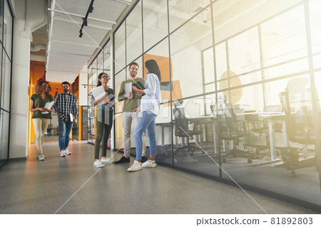 Full-length photo of positive young coworkers in office building 81892803
