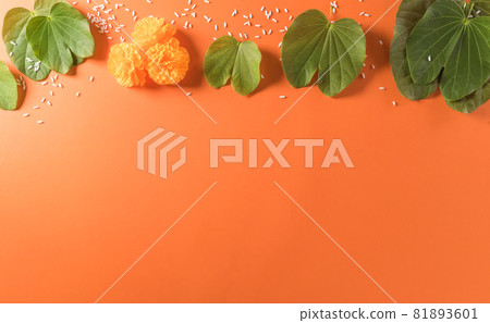 Happy Dussehra. Yellow flowers, green leaf and rice on orange background. Dussehra Indian Festival concept. Happy Dussehra. Yellow flowers, green leaf and rice on orange background. Dussehra Indian Festival concept. 81893601