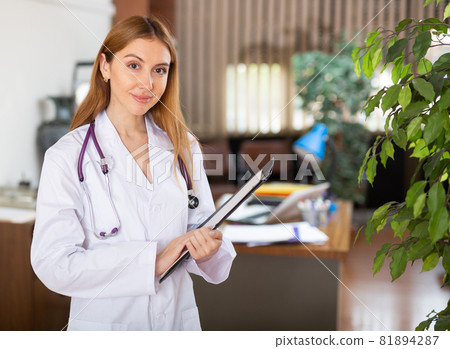 Female doctor standing in hall and smiling Female doctor standing in hall and smiling 81894287