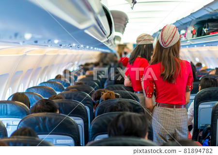 air hostess in red uniform services and checks for all correct at all around the passenger seat 81894782