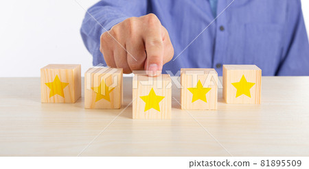 Hand touching wooden cube with five star shape on desk 81895509