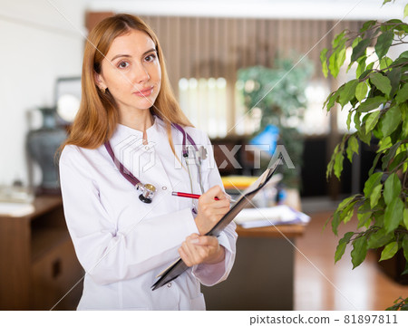 Female doctor standing in hall and smiling Female doctor standing in hall and smiling 81897811