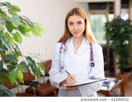 Female doctor standing in hall and smiling Female doctor standing in hall and smiling 81898052