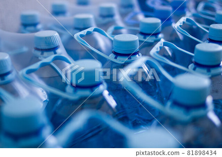 Many blue plastic bottles with blue caps with mineral water in a supermarket. Close Up. Main subject of a focus Many blue plastic bottles with blue caps with mineral water in a supermarket. Close Up. Main subject of a focus 81898434
