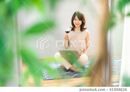 Young woman having a video chat over a glass of wine Young woman having a video chat over a glass of wine 81898626