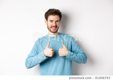 Good choice. Attractive caucasian man with beard showing thumbs up and smiling, like and approve good product, recommending something, standing on white background 81898743