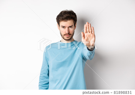 Serious young man looking confident with hand stretched out, saying stop, prohibit something bad or give warning, standing over white background Serious young man looking confident with hand stretched out, saying stop, prohibit something bad or give warning, standing over white background 81898831
