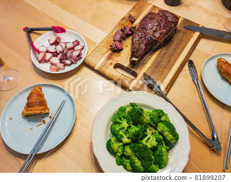 Close up shot of Tomahawk steak with vegetable and octopus leg Close up shot of Tomahawk steak with vegetable and octopus leg 81899207
