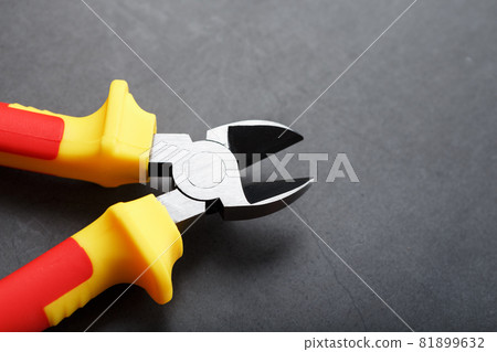 Pliers are a cutting tool with a red handle on a black background 81899632