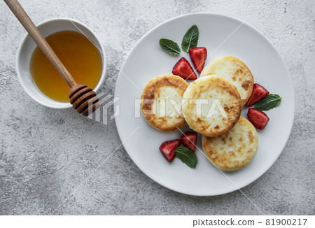 Cottage cheese pancakes, ricotta fritters on ceramic plate with  fresh strawberry. 81900217