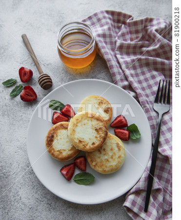 Cottage cheese pancakes, ricotta fritters on ceramic plate with  fresh strawberry. 81900218