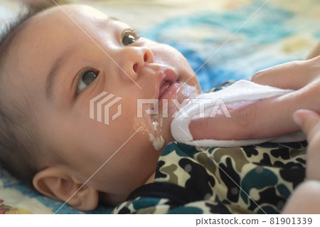 asian mother is wiping her baby's face after infant baby boy vomiting with soft sunbeam. people and family lifestyle concept. asian mother is wiping her baby's face after infant baby boy vomiting with soft sunbeam. people and family lifestyle concept. 81901339