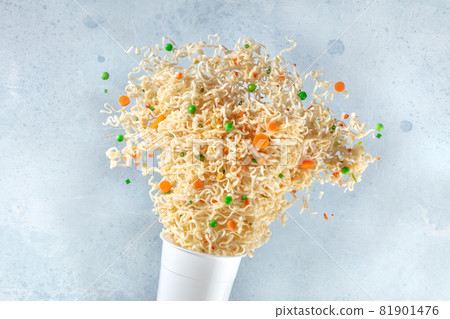 Ramen cup with instant noodles flying out of it 81901476
