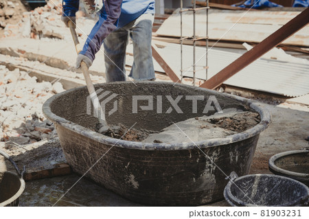 Worker man house builder mix mortar from a trough in bucket 81903231