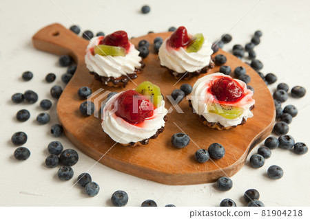 cupcakes with cottage cheese on vintage tray-tasty muffin with strawberry and kiwi on wooden plate 81904218