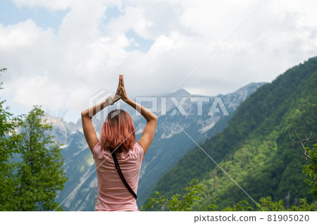 Young woman standing in nature with her hands joined above her head Young woman standing in nature with her hands joined above her head 81905020