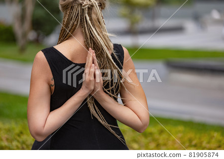 Close-up shot of beautiful woman with blonde hair doing yoga exercise in green public park in summer morning, outdoors. Healthy lifestyle, mental health concept. Close-up shot of beautiful woman with blonde hair doing yoga exercise in green public park in summer morning, outdoors. Healthy lifestyle, mental health concept. 81905874
