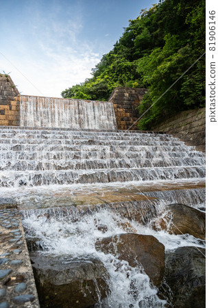A cold summer river with high transparency flowing through a dam that blends in naturally 81906146