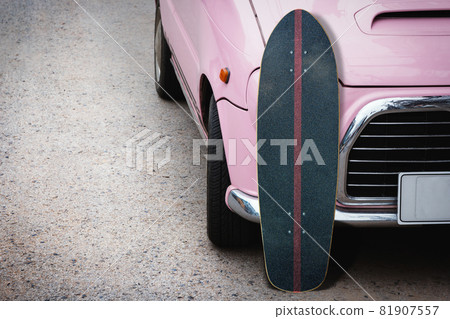 Old surfskate with pink vintage car on road in the parking. Old surfskate with pink vintage car on road in the parking. 81907557