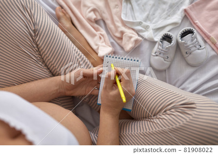 Top view of pregnant woman in the bed preparing baby clothes at home 81908022