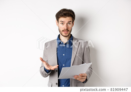 Confused businessman looking at bad document, complaining on deal, pointing at paper frustrated, standing in suit on white background Confused businessman looking at bad document, complaining on deal, pointing at paper frustrated, standing in suit on white background 81909447