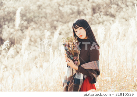 A woman holding a bouquet on a plateau where Japanese pampas grass spreads 81910559