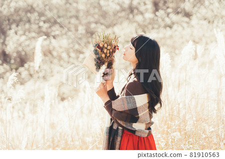 A woman holding a bouquet on a plateau where Japanese pampas grass spreads A woman holding a bouquet on a plateau where Japanese pampas grass spreads 81910563