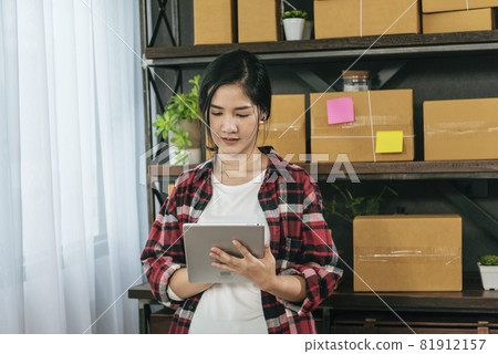 Asian woman startup small business at home office. Online seller entrepreneur young asian woman use tablet checking online order. Woman using tablet check stock goods supply delivery package shipping 81912157