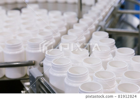 white plastic bottle on the production line of the conveyor at filling machine in the medical factory. selective focus. white plastic bottle on the production line of the conveyor at filling machine in the medical factory. selective focus. 81912824
