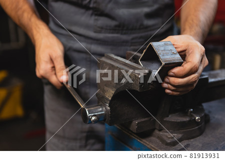 Close-up hands of male auto mechanic in dungarees with work tools working at car service station, indoors. Concept of labor, occupation, business, caree, job 81913931
