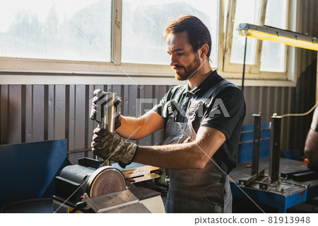 One young man, male auto mechanic, employee in dungarees making car service at garage, indoors. Concept of labor, occupation, business, caree, job 81913948