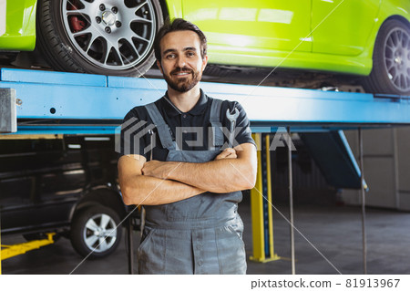 Young Caucasian man, male auto mechanic in dungarees working at car service station, indoors. Concept of labor, occupation, business, caree, job 81913967