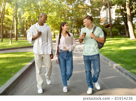 Three multiracial high-school students walking after study and talking in university campus outdoors Three multiracial high-school students walking after study and talking in university campus outdoors 81914236