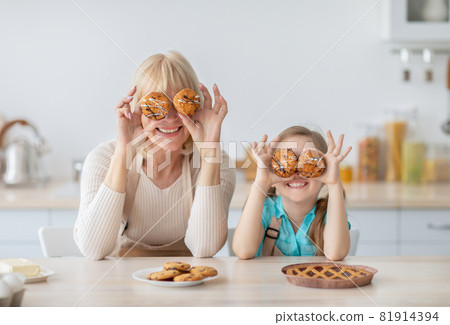 Granny and granddaughter playing with food in the kitchen Granny and granddaughter playing with food in the kitchen 81914394