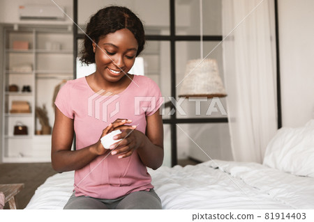 African American Lady Applying Hands Cream Moisturizing Skin In Bedroom 81914403