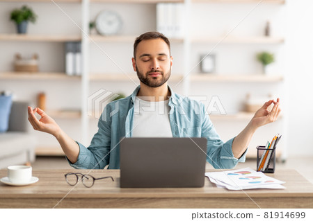 Workplace stress management. Calm Caucasian man meditating with closed eyes in front of laptop pc at home office Workplace stress management. Calm Caucasian man meditating with closed eyes in front of laptop pc at home office 81914699