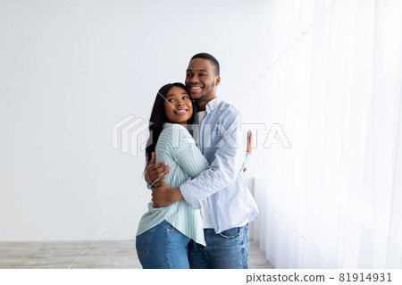 Happy young black spouses standing in their own house, hugging and smiling, being happy of buying own lodging 81914931
