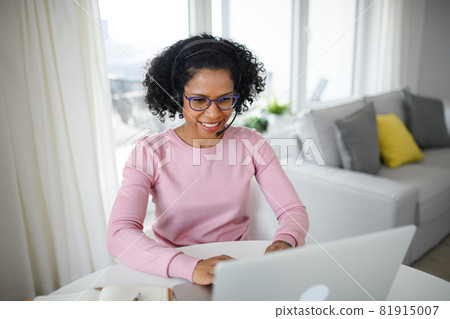 Portrait of happy mature woman with headset working on laptop indoors, home office concept. 81915007
