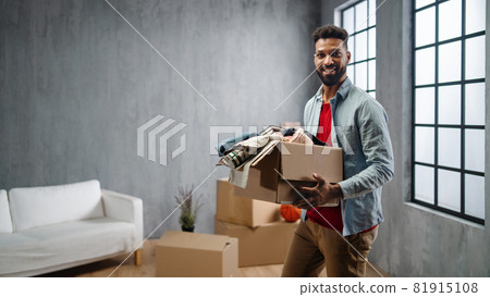 Happy young man holding packing boxes moving home, looking at camera, new living concept. 81915108