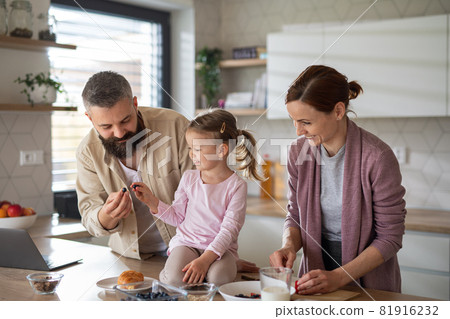 Family with small daughter indoors in kitchen at home, everyday life and home office with child concept. 81916232