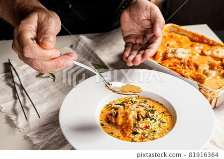 Authentic Spanish paella with cod and mussels. Traditional Mediterranean seafood dish. The chef prepares the dish. Restaurant dish serving. Close-up. People at work. Body parts Authentic Spanish paella with cod and mussels. Traditional Mediterranean seafood dish. The chef prepares the dish. Restaurant dish serving. Close-up. People at work. Body parts 81916364