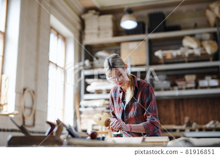 Portrait of female carpenter with goggles working on her product. Small business concept. 81916851
