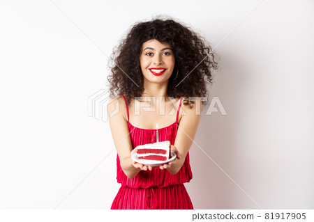 Beautiful woman congratulate with birthday, stretch out bday cake with candle and smiling, standing against white background 81917905