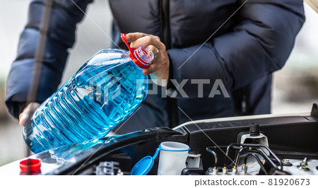 The male driver pours antifreeze into the tank to spray the windshield 81920673