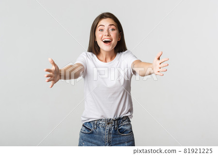 Excited beautiful girl extend hands forward, reaching for hug and smiling 81921225