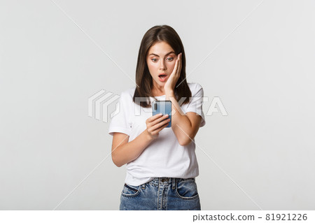Shocked and impressed brunette girl looking amazed at smartphone screen 81921226