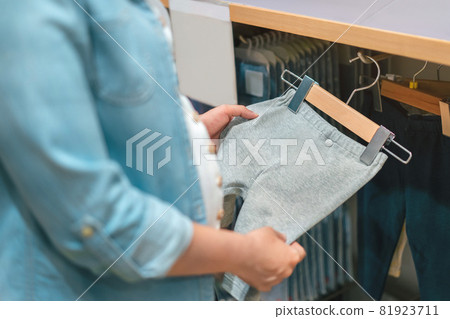 Happy pregnant asian woman choosing baby clothes at baby shop store, Prepare before Give birth baby concept. 81923711